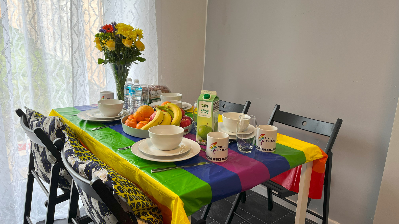 Table laid with rainbow cloth, fruit and flowers