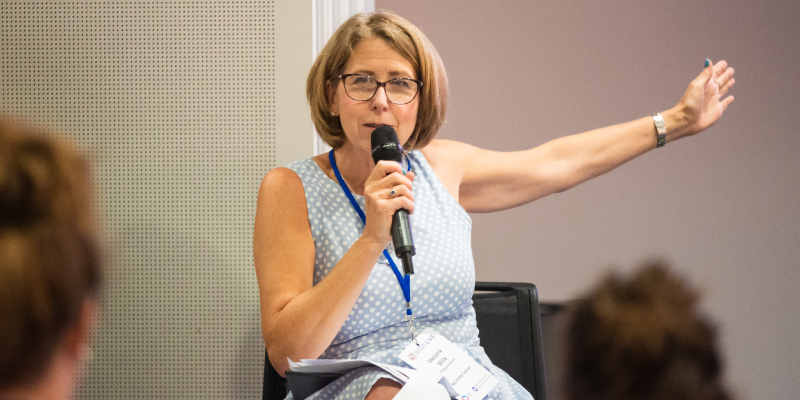 A woman speaking into a microphone while seated