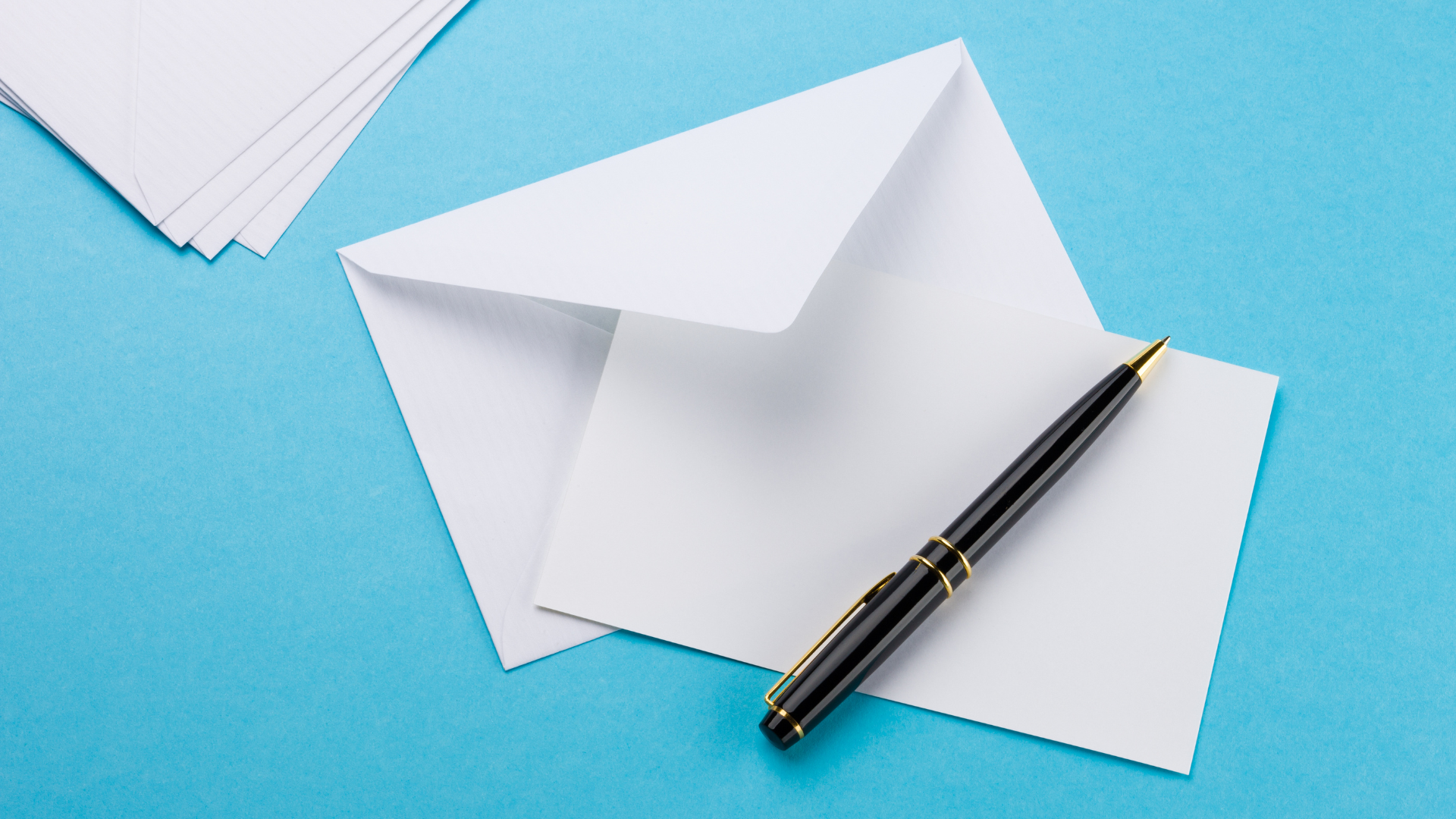 Image of a pen, paper and an envelope on a blue background