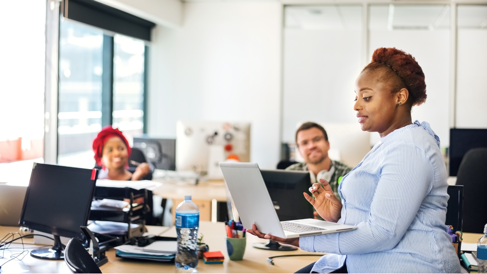 A woman looking at a laptop screen while her colleagues look on in the background
