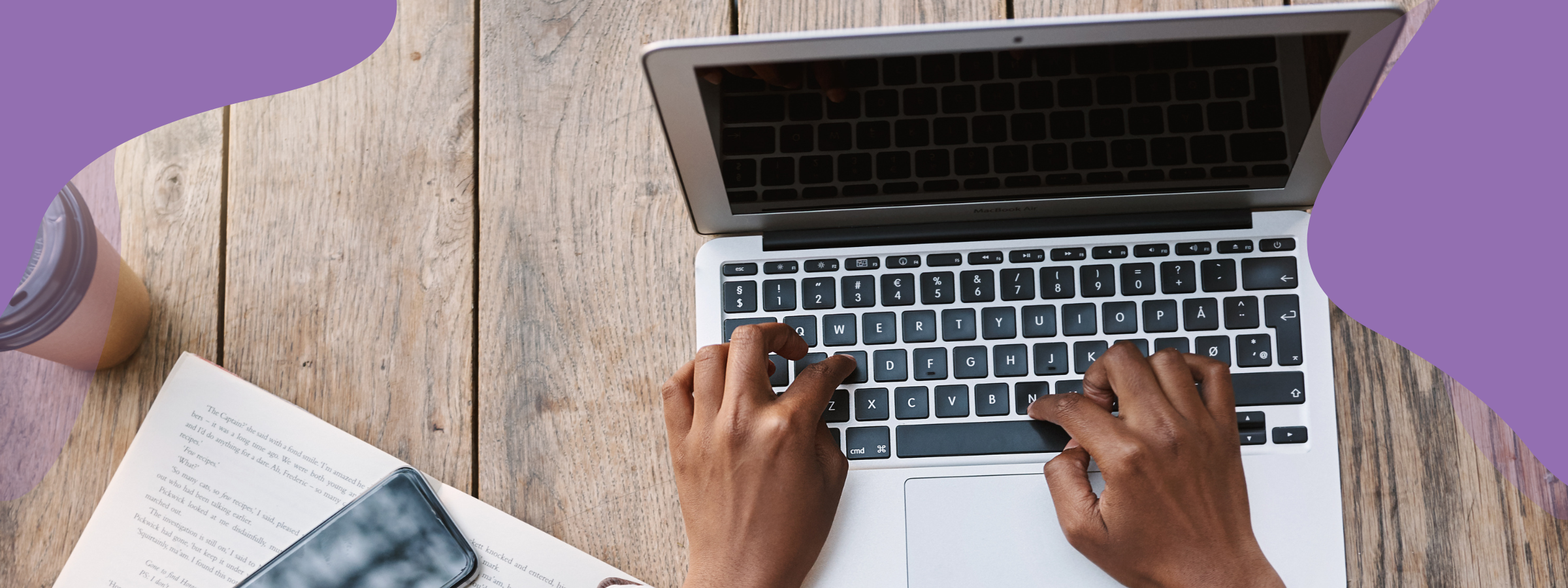 A birds eye view of a person typing on laptop with a coffee and notepad to the side