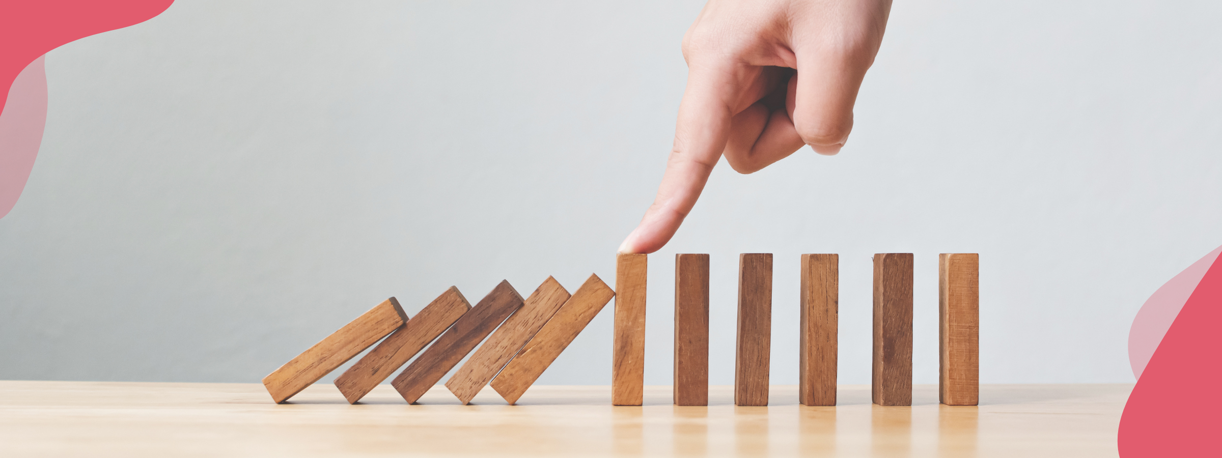 A row of dominoes with a hand stopping them from all toppling