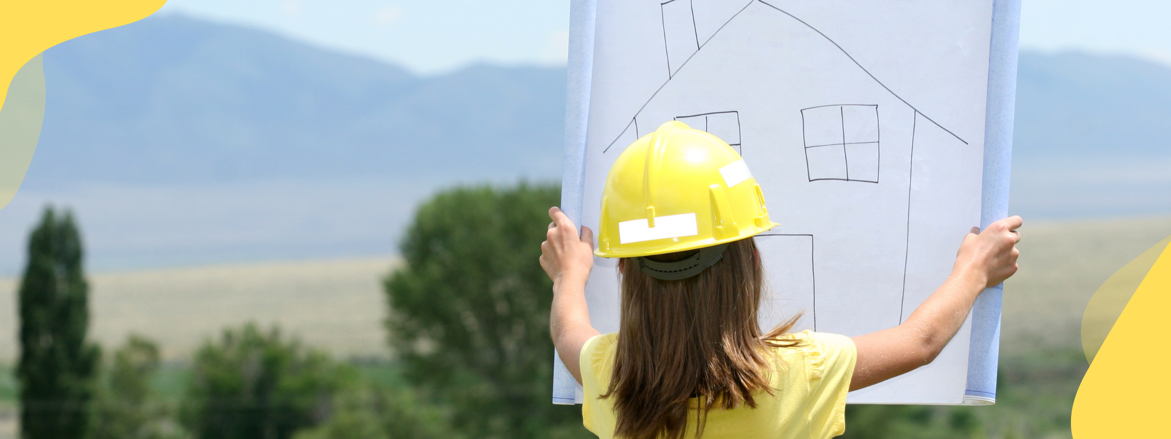A little girl wearing a hard hat and high vis jacket looks at a drawing of a house