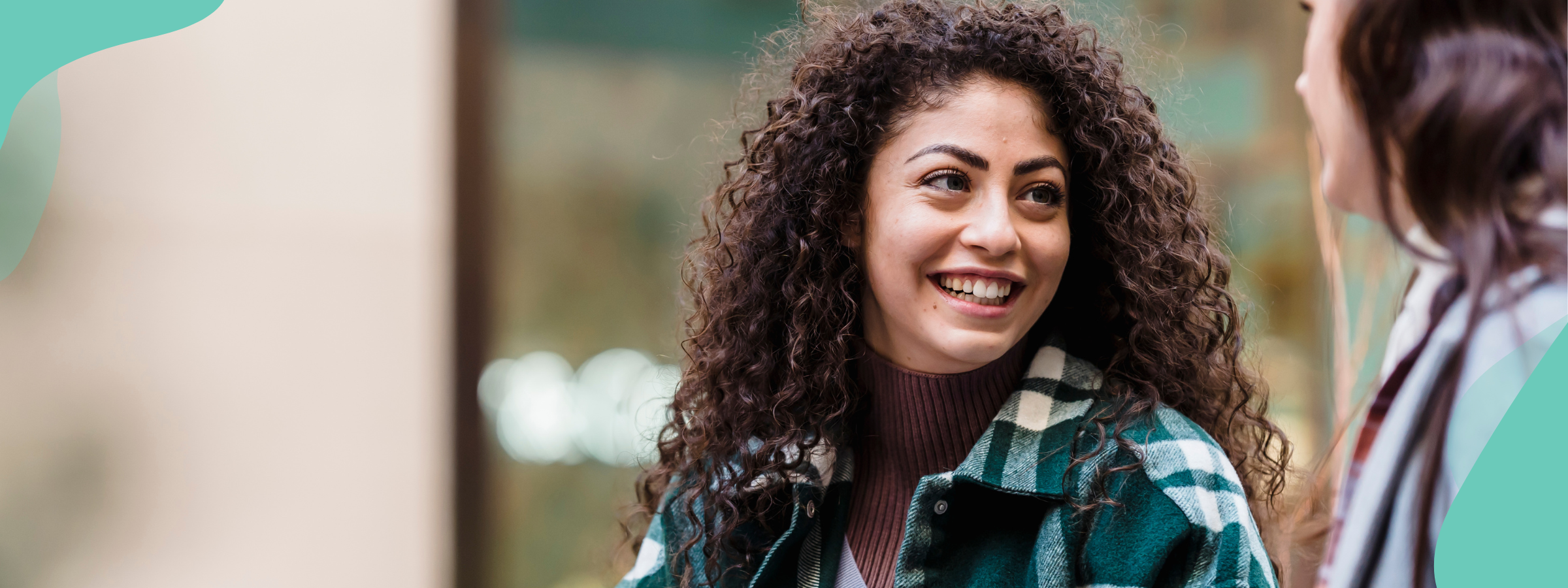 A young woman with brown curly hair smiling