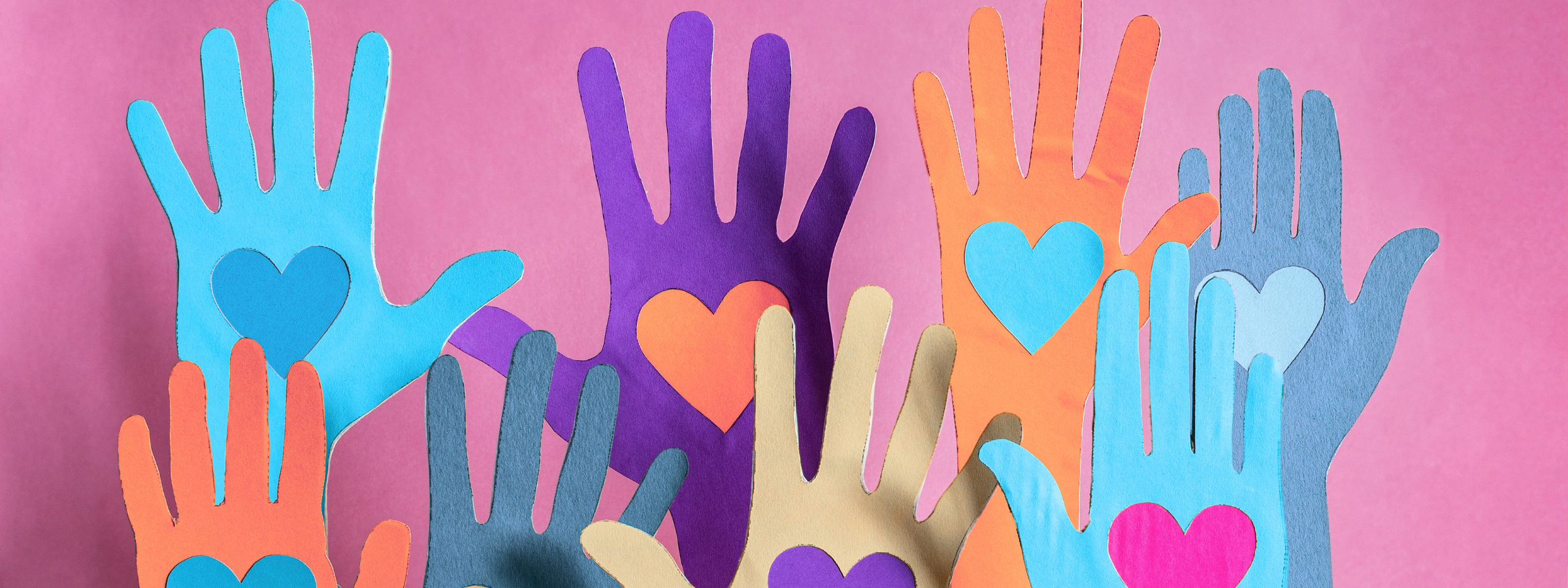 Colourful cut out paper hands with heart shapes in the middle