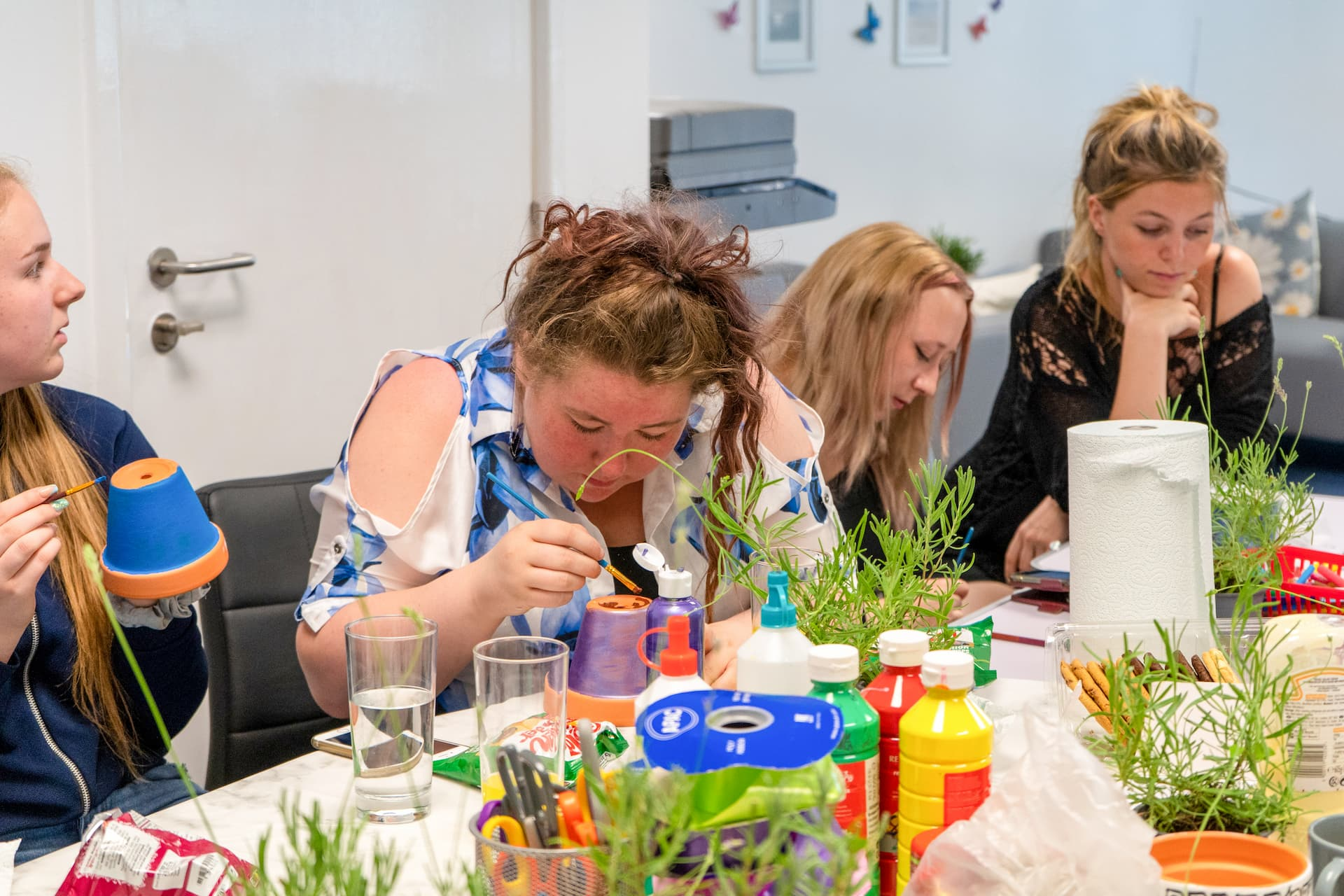 a group of women painting plant pots