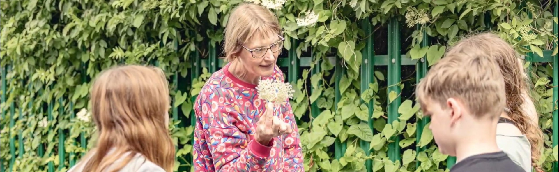 A woman and three kids standing in a garden.