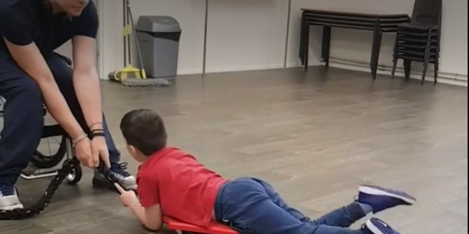 Louis encourages a young client – building core strength.(Taken as a still from video on theitr website)