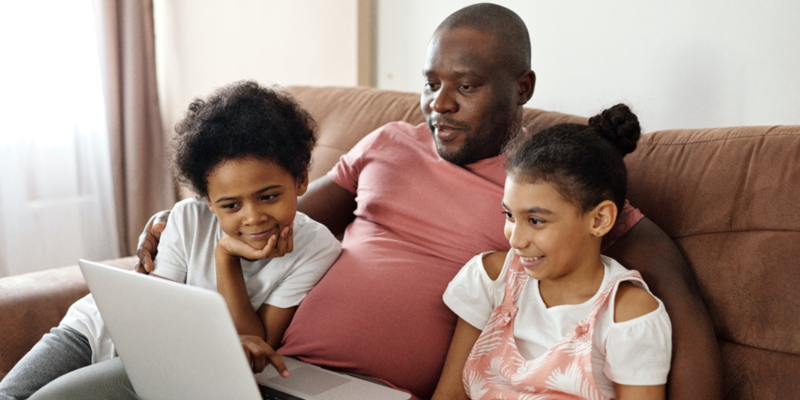 Man and two children gathered around a laptop 