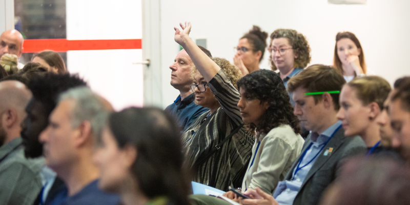 Woman in audience raises her hand 