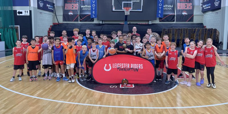 Group of young children from Leicester Riders Foundation standing together collecting a sports award in a basketball court