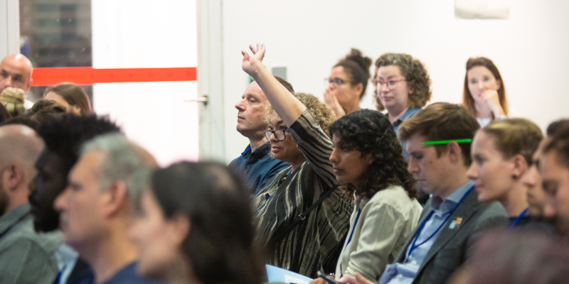 Woman in audience raises her hand