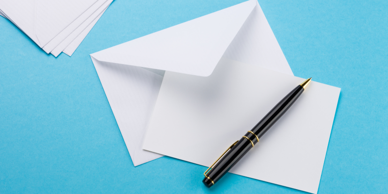 Image of a pen, paper and an envelope on a blue background