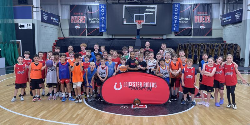 Group of young children from Leicester Riders Foundation standing together collecting a sports award in a basketball court