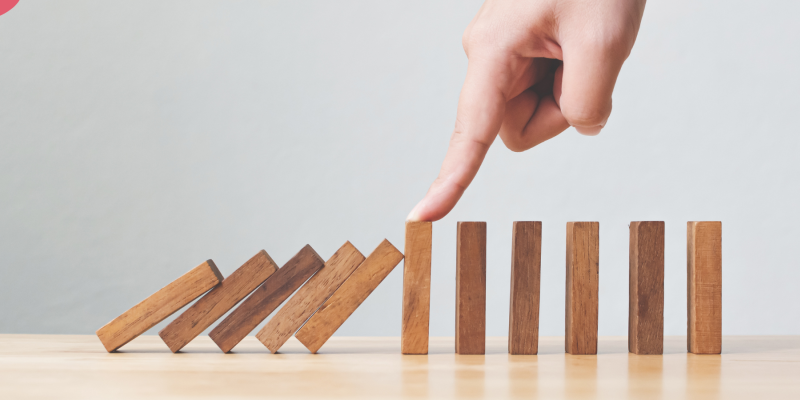 A row of dominoes with a hand stopping them from all toppling
