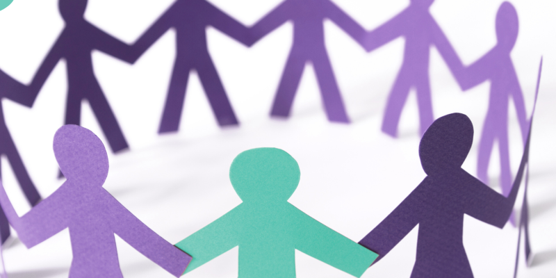 A group of purple paper cut out people in a circle holding hands