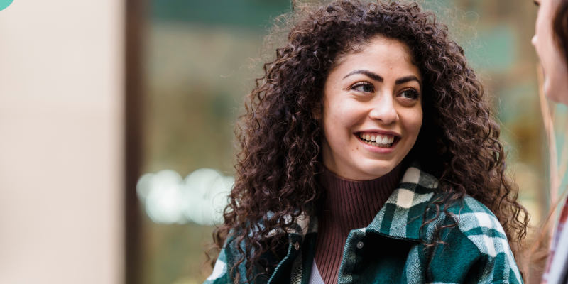 A young woman with brown curly hair smiling